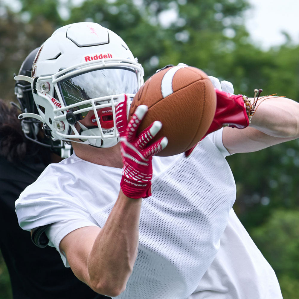 Lifestyle Image of Youth Football Player Wearing Rev 5.0 Receiver Gloves in Red
